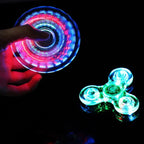 Hand holding a glowing LED spinner with another spinner on a black background